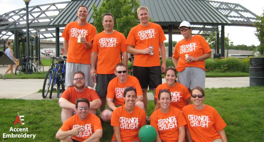 A diverse group of people in orange shirts, enthusiastically holding a ball, representing promotional spirit and teamwork